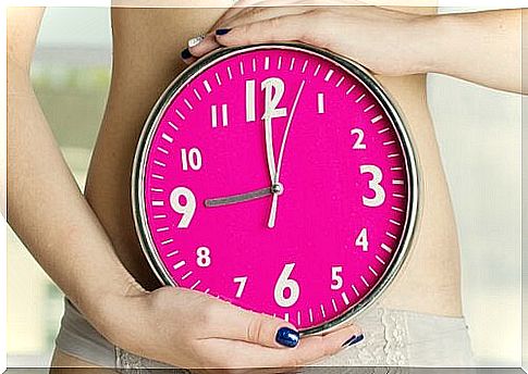 Girl holding a clock in front of her belly