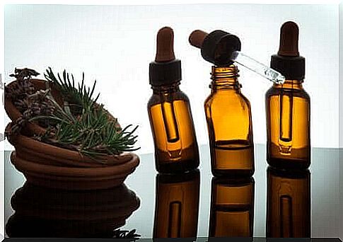 Three bottles of essential oils and a bowl of herbs