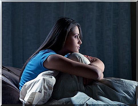 Woman sitting upright in bed in the dark