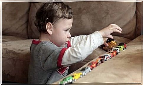 A child lines up toy cars