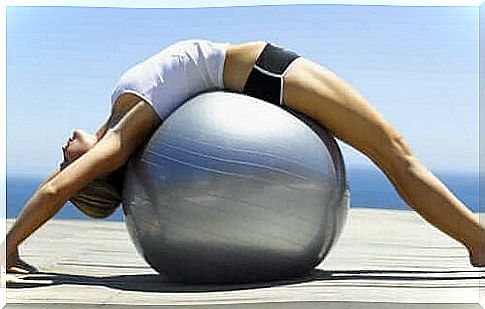 A woman lies on a pilates ball