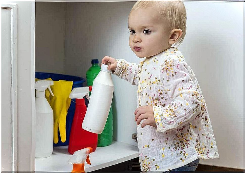 Toddler is holding a bottle of cleaning agent